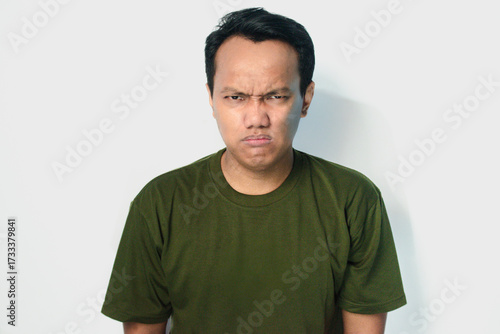 Quadro su tela Angry and mad face of Asian man in dark green shirt on isolated white background