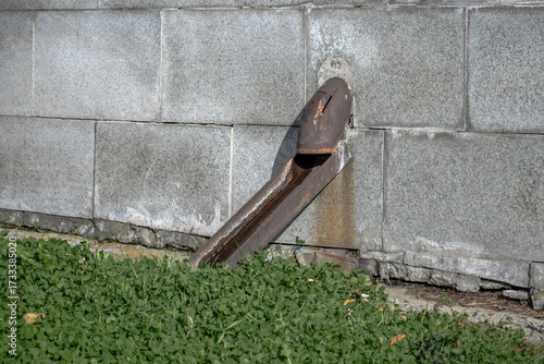 A fragment of a rusty downpipe on the wall of a house on an autumn day