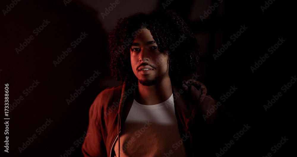 Obraz premium Confident male model with curly hair posing under red light in a professional studio photoshooting