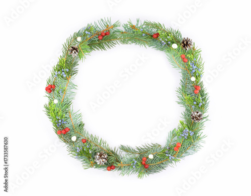 A Christmas wreath of fir branches decorated with berries, isolated on a white background. A Christmas design element.