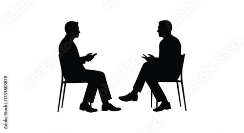 Two individuals in suits are seated facing each other in conversation