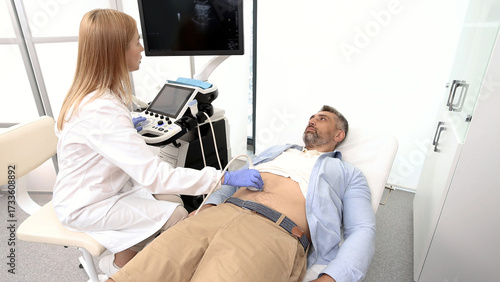 Ultrasound specialist doing ultrasonography of abdominal cavity for male patient with ultrasound machine at hospital