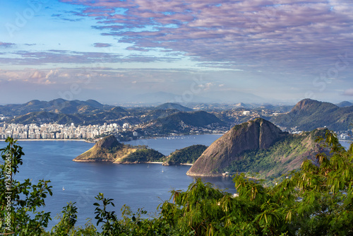 Foto Expansive view of Guanabara Bay and the city of Rio de Janeiro, highlighting Morro da Urca and Pao de Acucar, with lush tropical foliage in the foreground