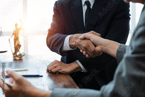 Business people in suits shaking hands after a successful legal meeting, finalizing an agreement in an office