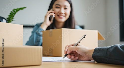 Joyful entrepreneur on phone handles orders amidst shipping boxes, planning growth