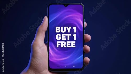 Hand holding modern smartphone displaying 'BUY 1 GET 1 FREE' special offer text on a vibrant digital background, symbolizing e-commerce discounts a...