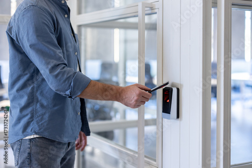 Man using smartphone for contactless access control at office door