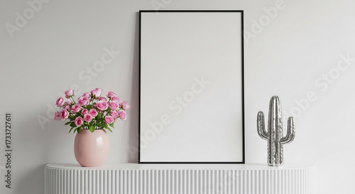 Blank picture frame, pink flowers, silver cactus on white shelf