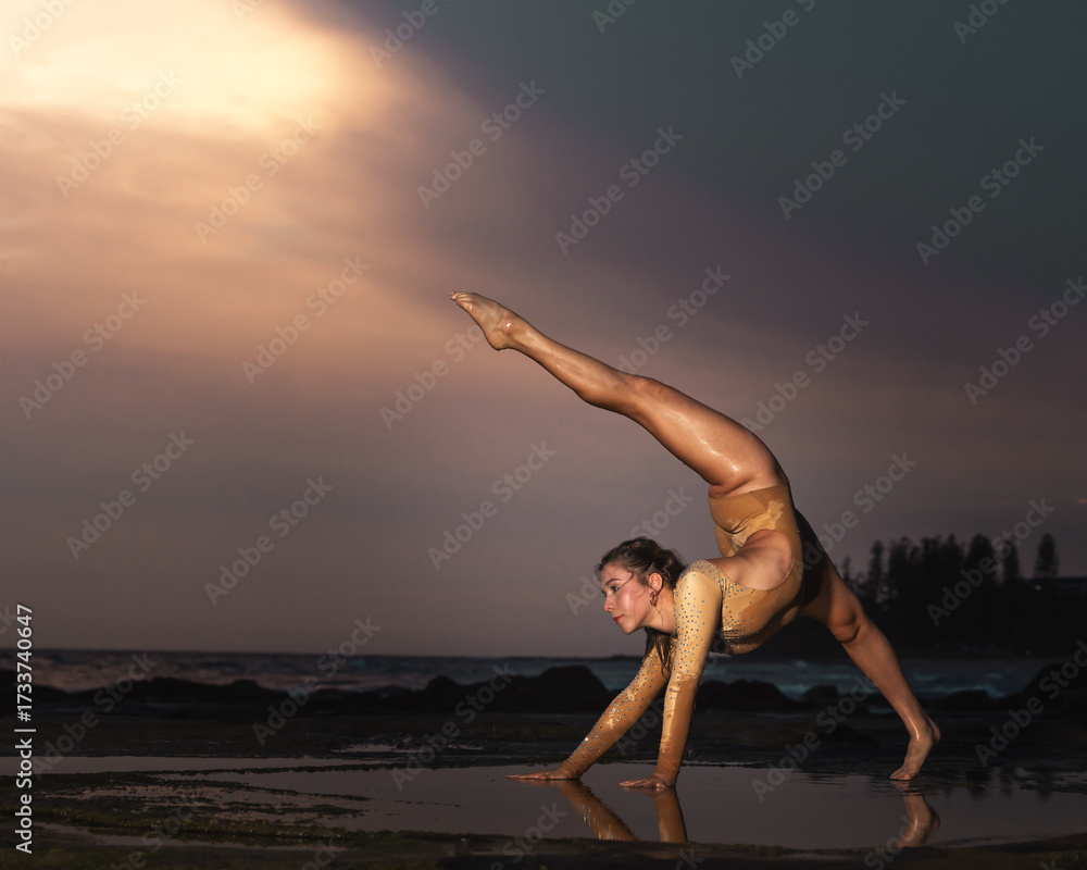 Obraz premium Elegant Contemporary Dance Pose at Sunset on the Beach – Powerful Female Dancer with Flexibility and Strength