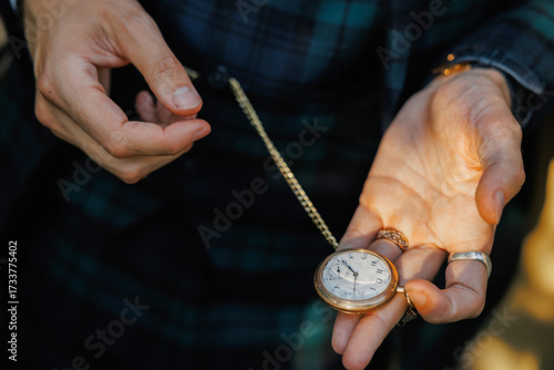 Close-up of a person's hands holding an antique gold pocket watch with a chain, showing vintage elegance, timeless style, and nostalgic craftsmanship in warm natural light