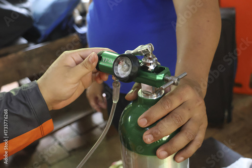 Medical oxygen tank adjustment for patient care, showing careful handling and relief medical health care equipment tank oxygen cylinder gauge pressure therapy breathing respiratory assistance help