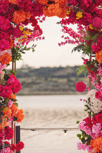Fotografie Vibrant floral archway frames a serene lakeside view at sunset, perfect for a ro