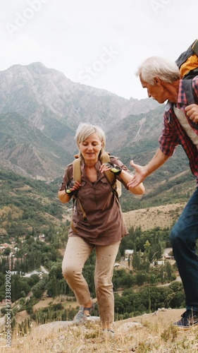 Vertical slow motion video mature couple trekking mountains with backpacks symbol family love relationship support healthy lifestyle active retirement travel freedom nature adventure together