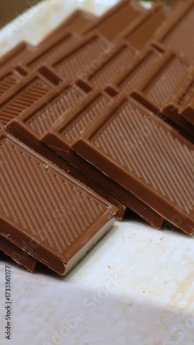Broken pieces of dark chocolate on a white plate. Close-up.