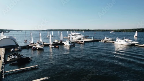 Yachts and speedboats are moored on the lake. Odis move from small waves on the water. Shooting in motion from the air