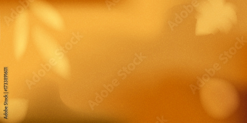 Soft golden blurred background with faint silhouettes of leaves. Autumn atmosphere for seasonal design, posters, wallpapers. Textured fall banner for sale, ad, invitation edc