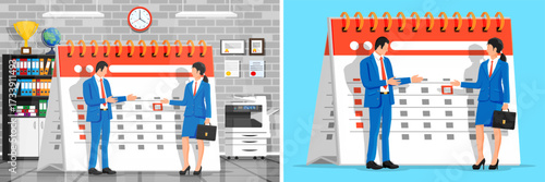 Man and woman stand near a large calendar. Business couple making plans or scheduling event. Team planning and management concept.