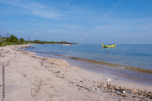 tropical beach with two fishing boats rest under a bright blue sky