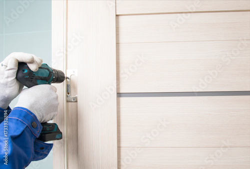 the master installs an interior door by screwing the hinge to the doorway, close-up