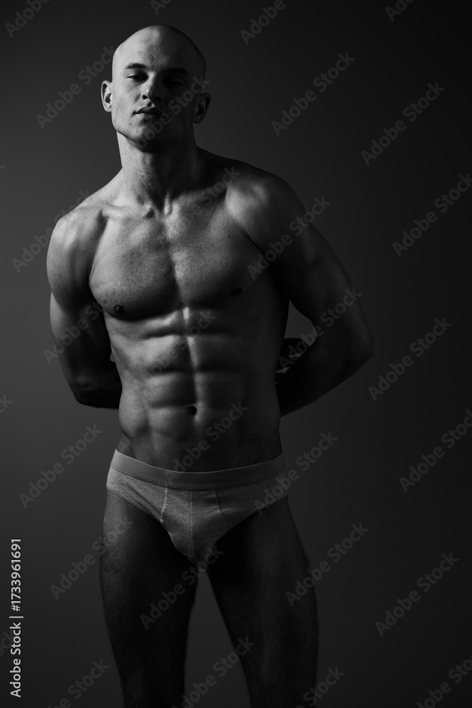 Naklejka premium Black and white portrait of a muscular man, showcasing strength and confidence, emphasizing his toned physique and powerful expression, ideal for fitness themes.