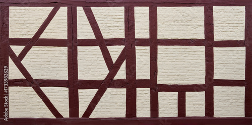 Restauriertes, neu gestrichenes altes Fachwerk aus braunen Balken gefüllt mit hellen Ziegelsteinen 