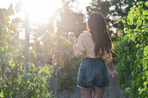 Young beautiful Smiling  italian woman walking at wineyard with a Glass of Red wine.Wine tourism at Tuscany,Italy