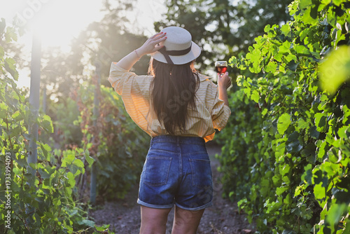 Young beautiful Smiling  italian woman walking at wineyard with a Glass of Red wine.Wine tourism at Tuscany,Italy