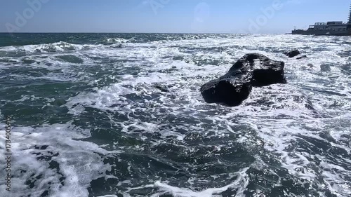 A storm at sea on a sunny day, white foam on the surface of the water
