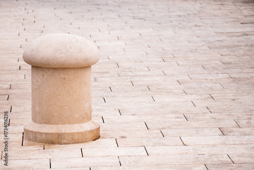 Stone mooring bollard on paved pier