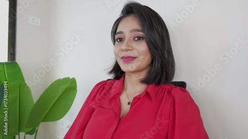 Closeup of happy smiling beautiful young businesswoman sits on chair looking at camera feels happiness confidence with satisfied calm face expression.