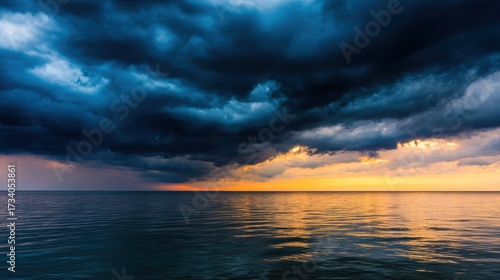 Dramatic sunset over calm ocean waters with dark storm clouds gathering on the horizon