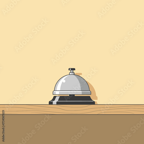 A silver bell sits on a wooden counter against a plain background.