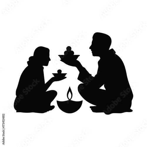 Couple performing traditional indian religious ritual with oil lamp and offerings silhouette