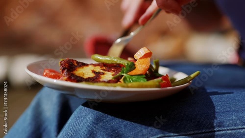 Woman eating salad with haloumi cheese and organic bio vegetables in sun