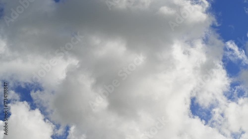 White fluffy clouds crossing the blue sky from left to right in timelapse. Fair-weather cumulus clouds. Dreamlike skyscape.