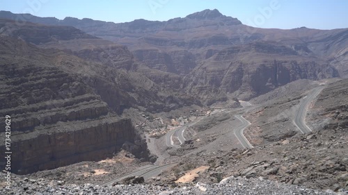Experience breathtaking landscapes with winding roads traversing dramatic mountain ranges in a remote desert area, showcasing the beauty of nature and isolation.