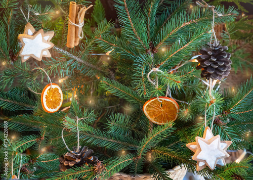 Christmas zero waste, rustic, eco. Closeup of decorated Christmas tree -  dried oranges, pine cones and cinnamon sticks, cookies. Eco-friendly Christmas.