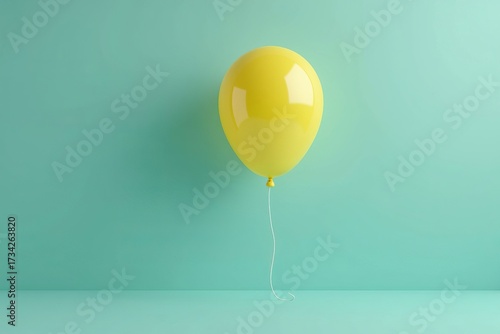 Joy and celebration concept with one single yellow balloon against a minimalist mint green background with copy space.
