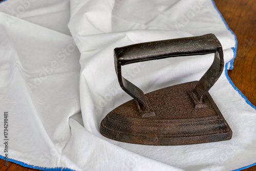 Close-up of an antique rustic flat iron on a white piece of fabric
