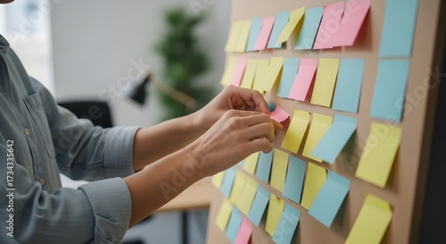 Business person managing project tasks with colorful sticky notes on a board.