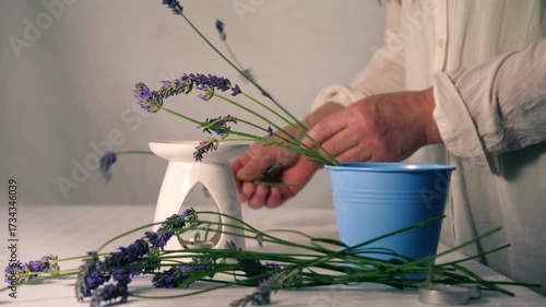 Woman with fresh lavender flowers for aromatherapy with oil burner and tea light candle 