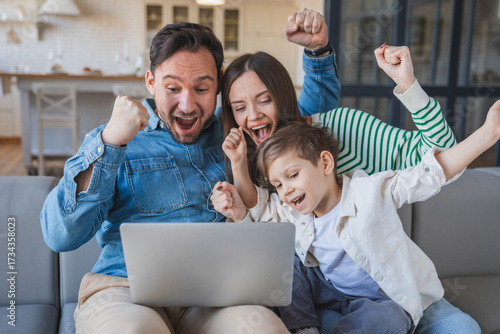 Foto Overjoyed family exult together in front of laptop sitting at home on the sofa