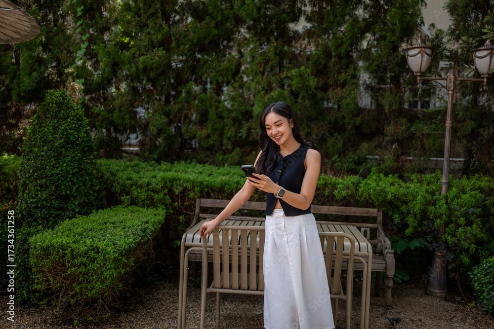 Naklejka premium Young woman enjoying connection with smartphone in garden