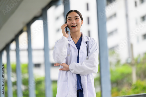 Asian female doctor having phone call walking in hospital