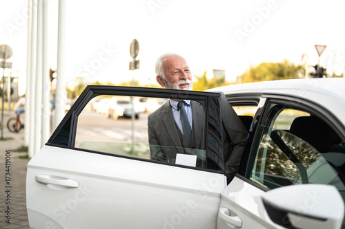 Bilde på lerret Senior businessman exiting car in city street