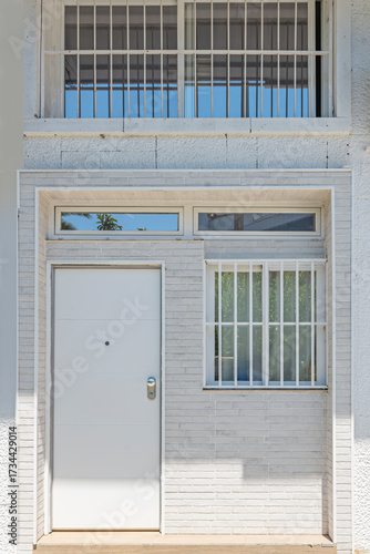 Minimalist loft apartment facade with a solid wood street-level door and a black aluminum side window in a renovated building