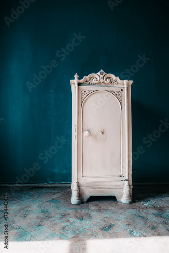 An antique safe in a room in an abandoned building. Blue walls. Light and shadows.