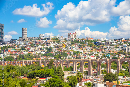 Urban landscape seen from the viewpoint of the arches, with buildings in the background and a blue sky with white clouds, in queretaro