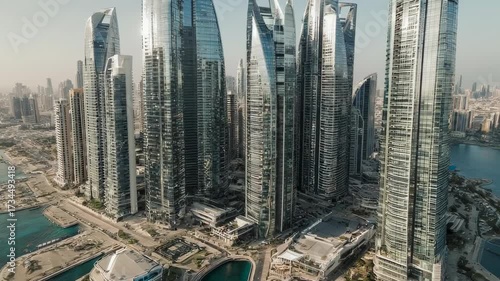 Aerial view of a modern city with tall buildings, waterfront, and a sunny day