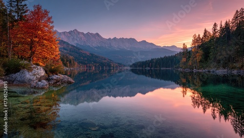 Serene lake with mountain backdrop, autumn foliage, and sunset hues